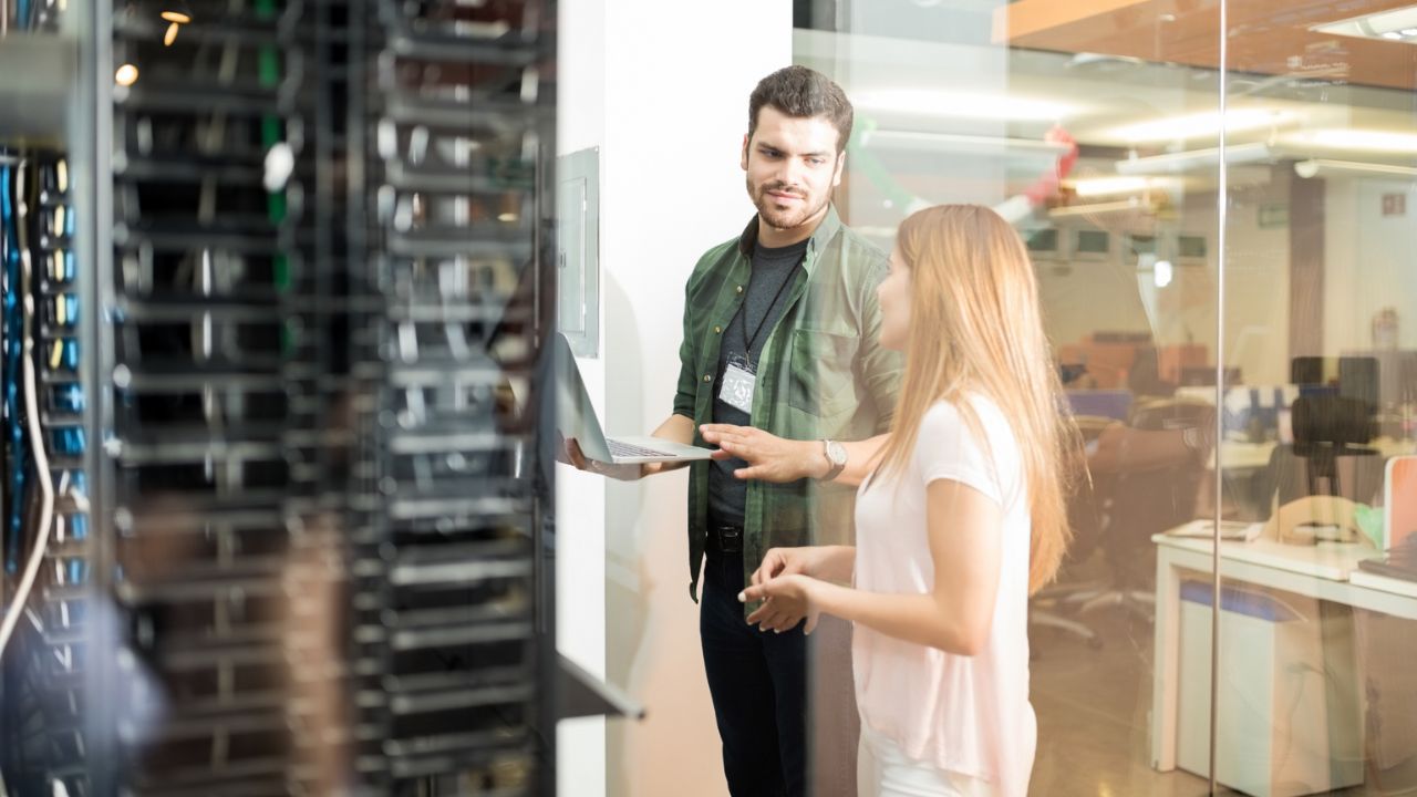 Technician installing dedicated servers in a secure cabinet at a colocation data center.